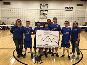 Boys volleyball team holding up a tournament champion banner